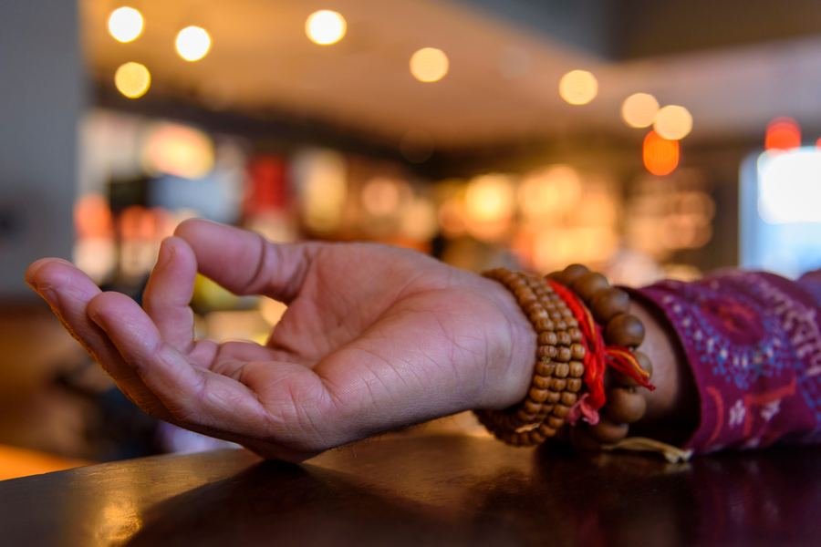 A hand resting in chin mudra with mala beads